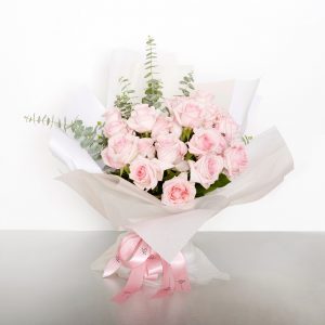 A classic bouquet of two dozen Columbian long stem pink roses accented with seasonal foliages - for soft and tender expressions. Image shows a 24 stem wrapped bouquet 55cmW x 60cmH