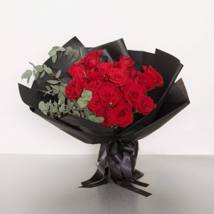 A classic bouquet of two dozen Columbian long stem red roses accented with seasonal foliages - the perfect expression of love! Image shows a 24 stem wrapped bouquet 55cmW x 60cmH